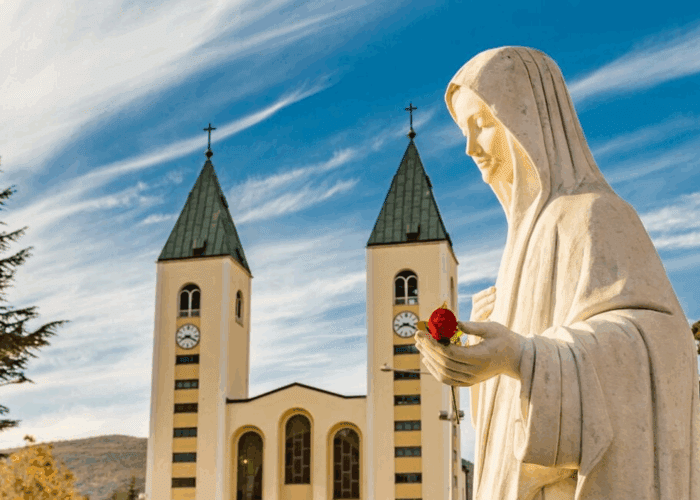 Statue of Our Lady of Medjugorje holding rose in front of St. James Church in Medjugorje